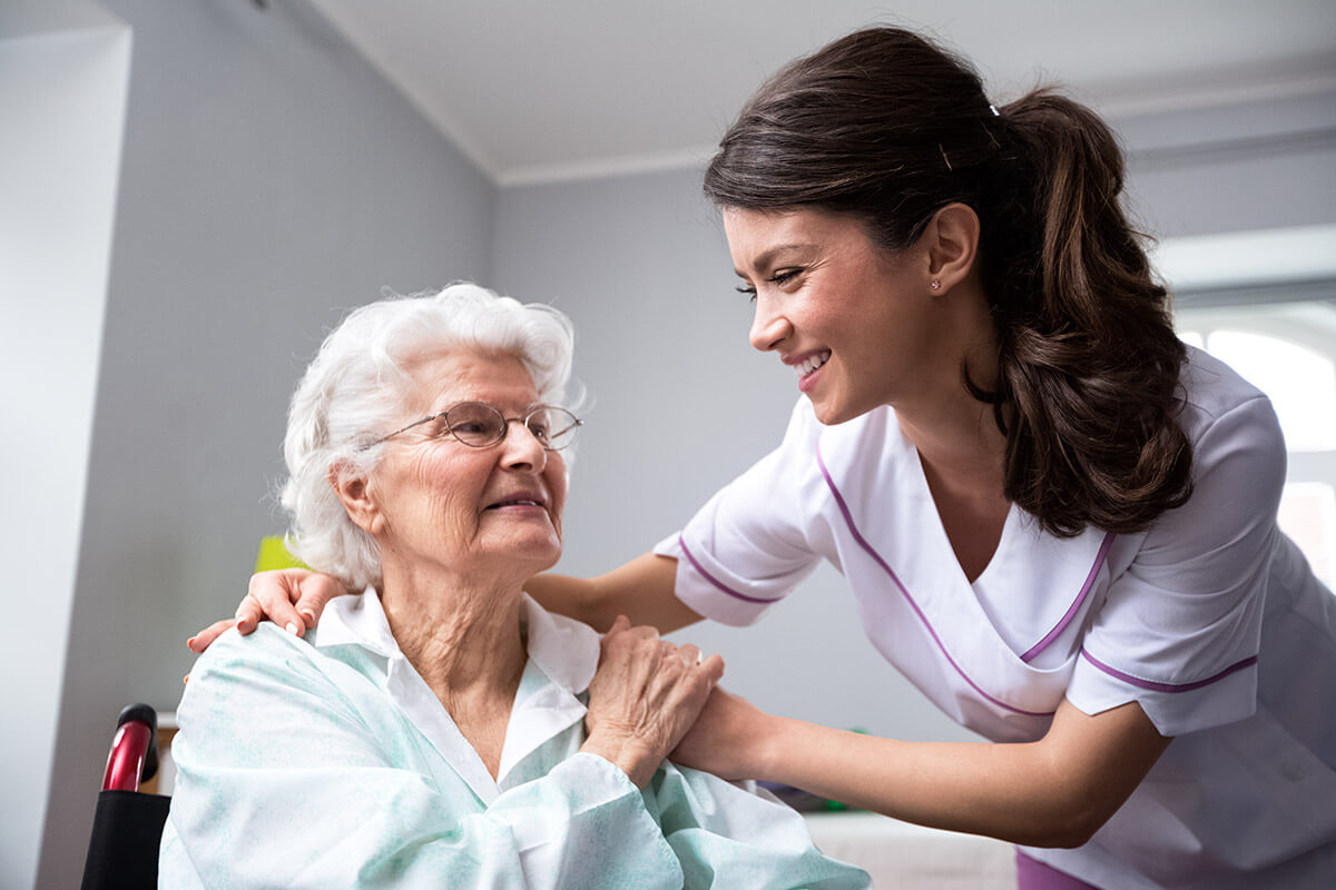 Smiling nurse and old woman patient